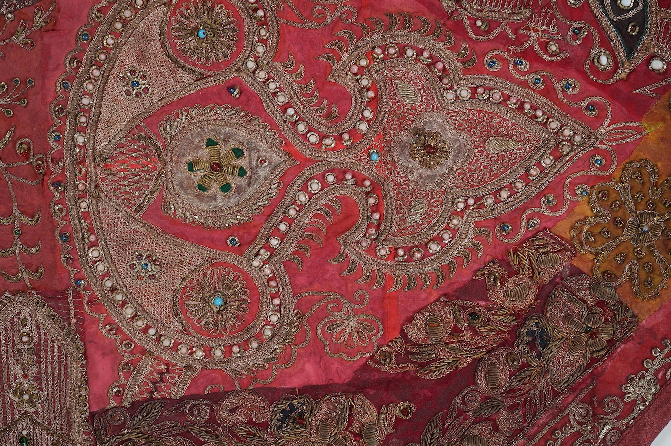 An Indian 20th century red silk marriage banner/hanging, ornately embroidered in silver and gold thread, with raised stump work flowers, corded and designed using simulated pearls and coloured beads etc., 74cm x 43cm. Co